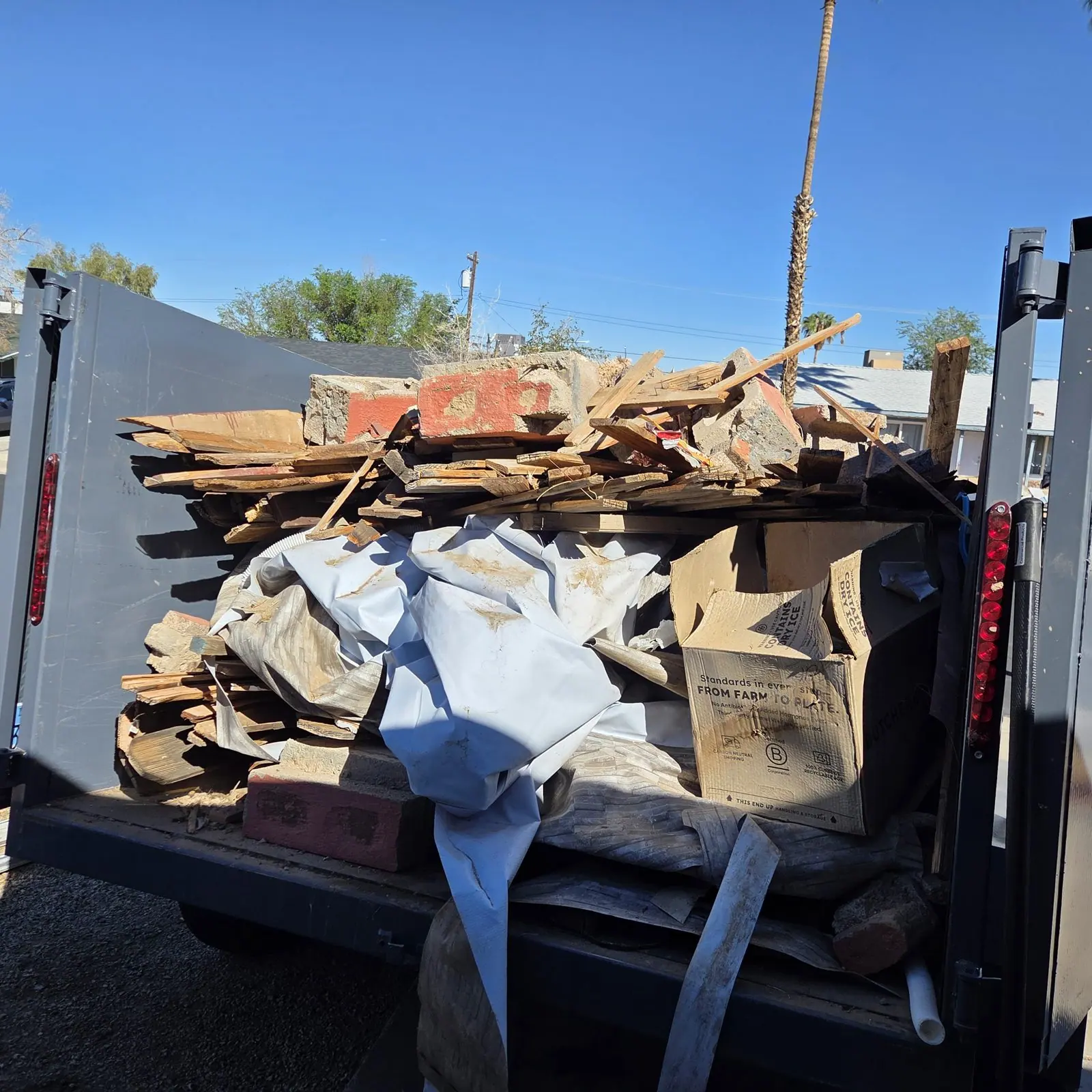 Henderson Junk Solutions trailer loaded with old fence boards, concrete-filled bricks and an old pool liner