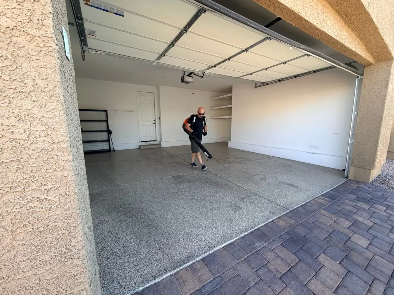 Henderson Junk Solutions crew member blowing dust and debris out of the cleared Cadence garage