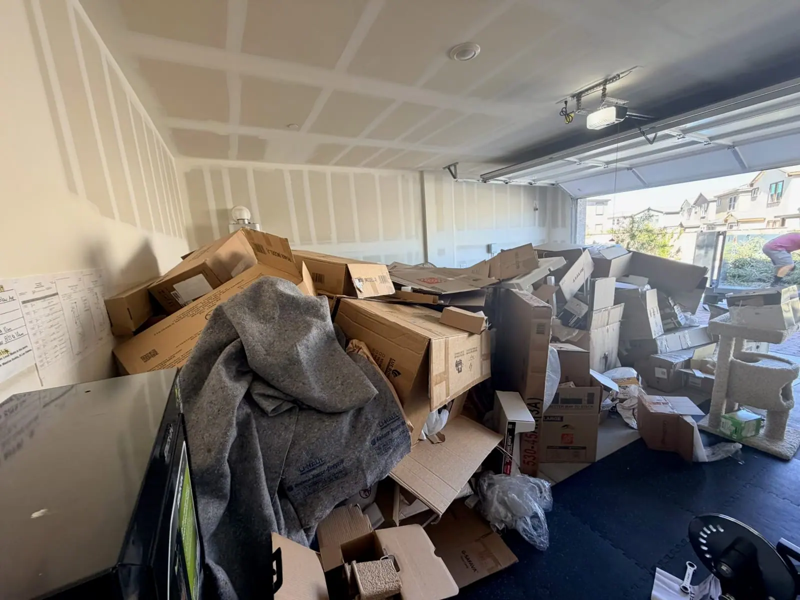 Inspirada garage filled with moving boxes, packing paper, styrofoam and a moving blanket after a family unpacked